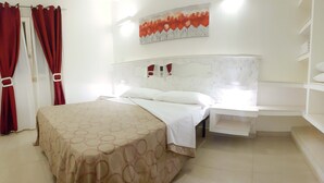 A hotel room with a bed, a nightstand, a built-in shelf, a painting on the wall, and a wardrobe. - Villa Gina - Torre San Giovanni with pool 5 minutes from the Maldives of Salento (Ugento)