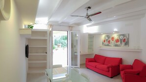 A modern living room with a glass dining table, red sofas, and a ceiling fan. - Villa Gina - Torre San Giovanni with pool 5 minutes from the Maldives of Salento (Ugento)