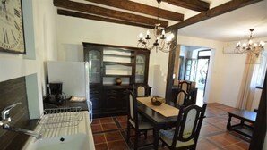 Une cuisine équipée d’un évier, d’une table à manger avec des chaises et d’un lustre.