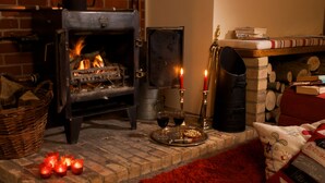 Una habitación acogedora con chimenea, un tapete rojo y una estantería llena de libros.