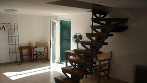 Eine Wendeltreppe in einem Raum mit Fliesenboden, einem Ventilator und einem Sessel.