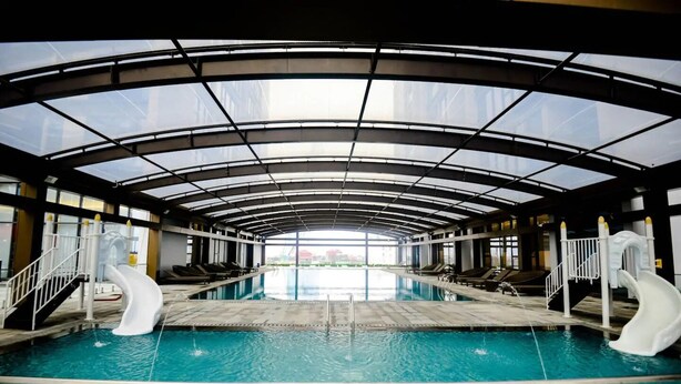 Une piscine intérieure dotée de deux toboggans, d’un toit en verre et offrant une vue sur l’extérieur.