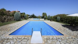 A rectangular swimming pool with a stone border and a metal ladder leading into it. - BEAUTIFUL SANI VILLA (Chalkidiki)