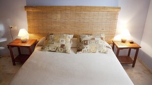 Un dormitorio con una cama grande, dos mesitas de noche con lámparas y un cabecero de bambú.
