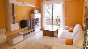 Una sala de estar moderna con televisor de pantalla plana, muebles de madera, un balcón con vistas y un equipo de aire acondicionado.