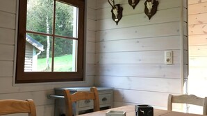 A dining area with a wooden table, chairs, and a window with a view of trees.