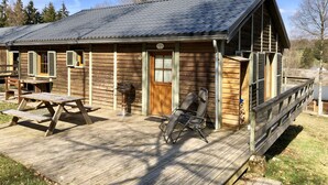 A wooden cabin with a porch, a grill, and a picnic table.