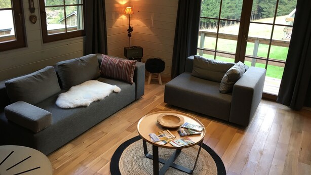 A cozy living room with two grey sofas, a wooden coffee table with magazines, and a lamp.