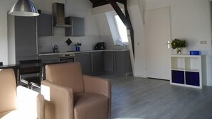 Une cuisine moderne dotée d’une verrière, un coin repas avec des chaises en cuir et une console blanche agrémentée d’un vase.