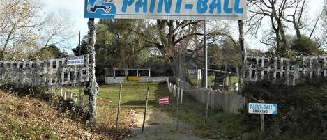 Een bord voor Paint-Ball, met een reserveringsnummer en een pad naar een omheind gebied.