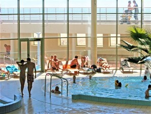 An indoor swimming pool area with multiple pools and lounge chairs.