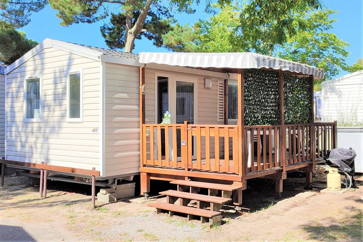 Ein Wohnmobil mit einer Holzterrasse und einer überdachten Veranda.