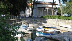 Un canal con barcos amarrados, un muro de piedra y un edificio con columnas al fondo.