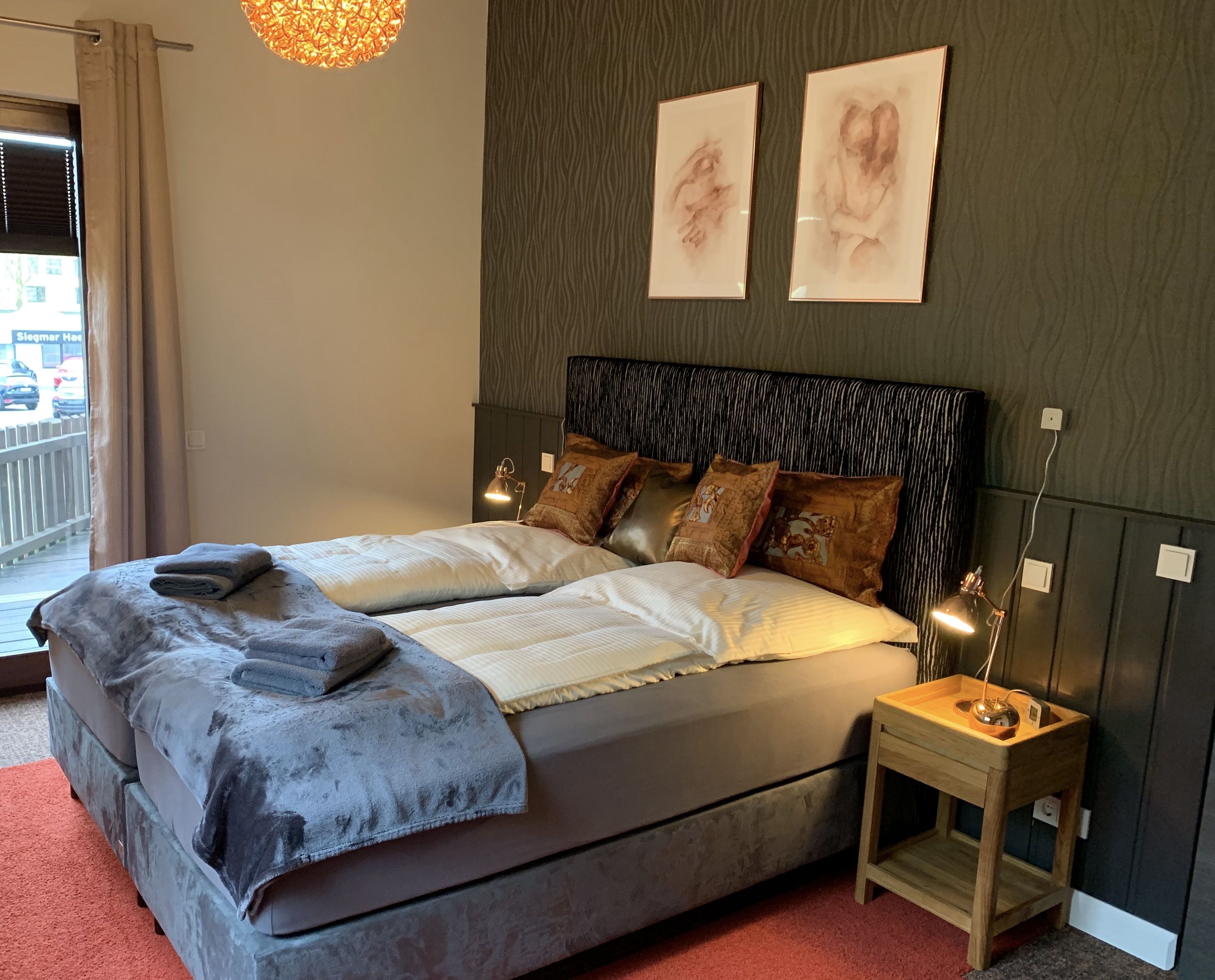 A modern bedroom with a large bed, two bedside lamps, and artwork on the wall.