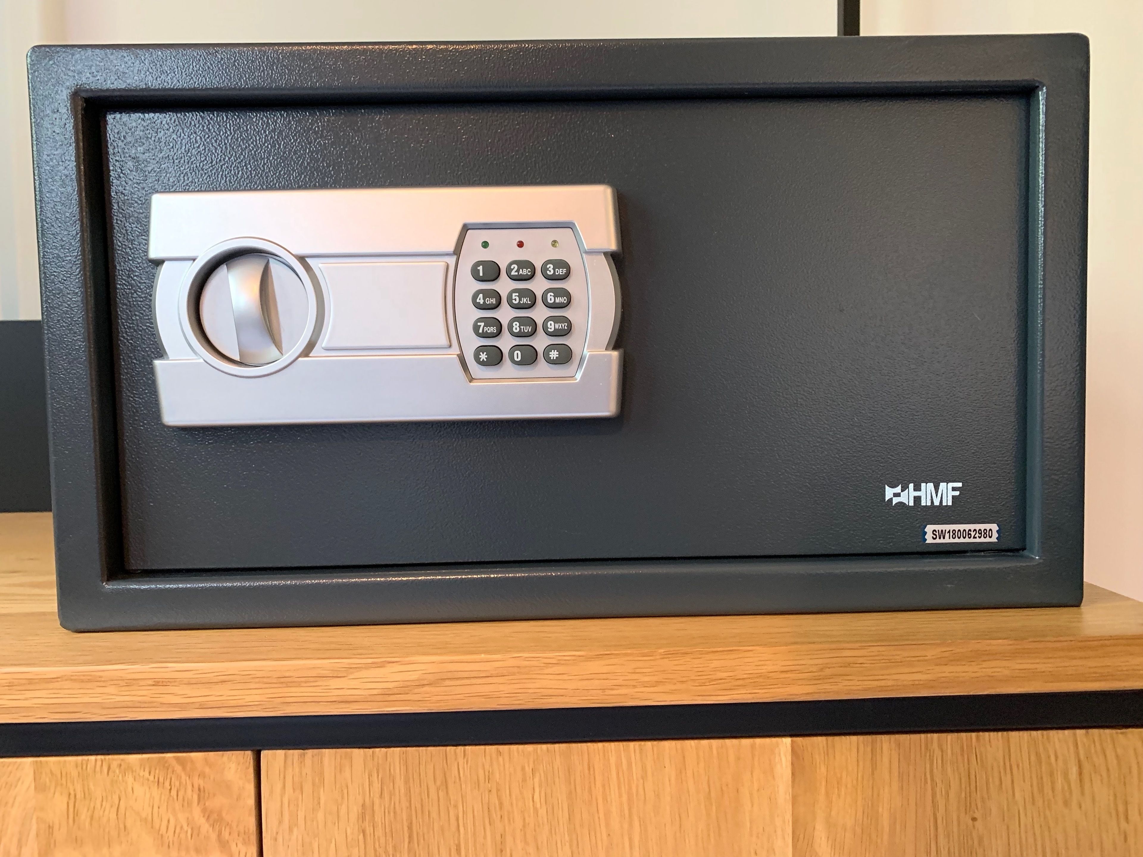 A safe deposit box with a combination lock and a keyhole, labeled with the brand HMF and a serial number SW180062980.