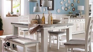 Una cocina con armarios blancos, encimera de mármol y pared azul decorada con platos.