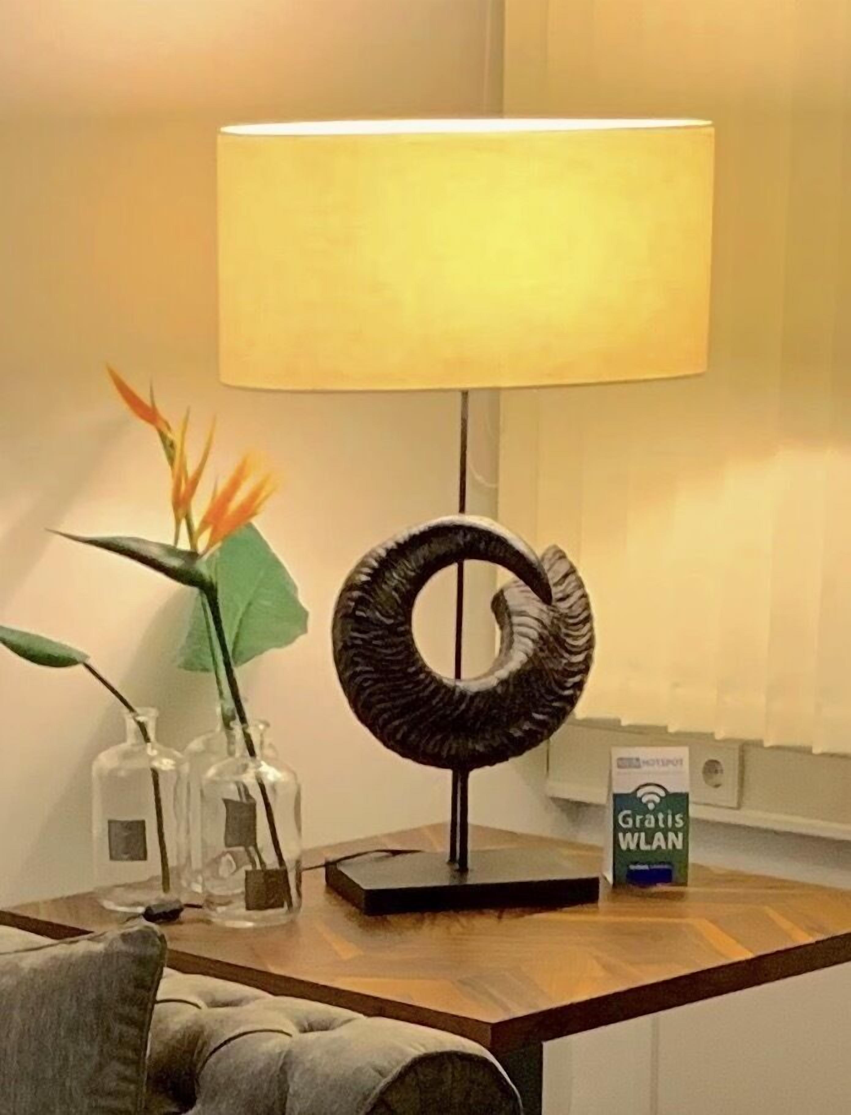 Una mesa con una lámpara, un objeto decorativo y un cartel que ofrece WLAN gratuita.