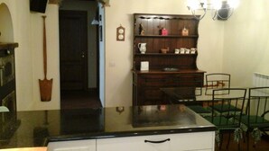 A kitchen with a wooden table, chairs, and a cabinet with kitchenware. -  Villa with own pool, mountain village with restaurant and shop. North of Lucca (Pieve Fosciana)