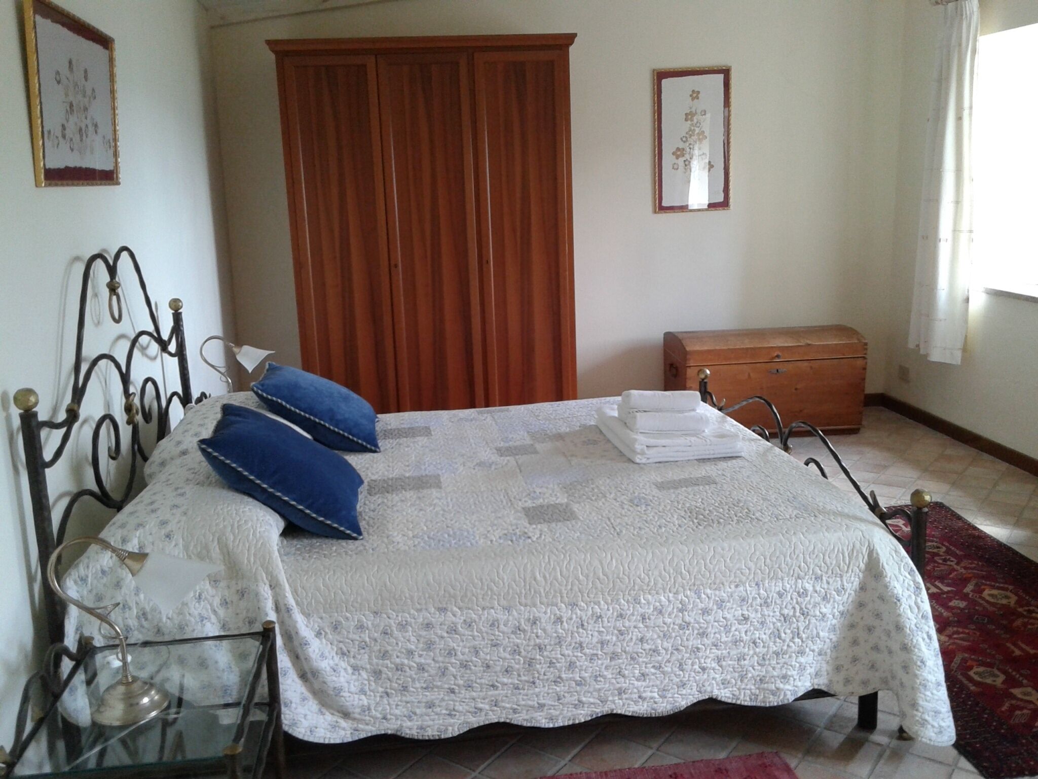 Une chambre à coucher avec un lit, une armoire en bois, une table de chevet et un tapis rouge.