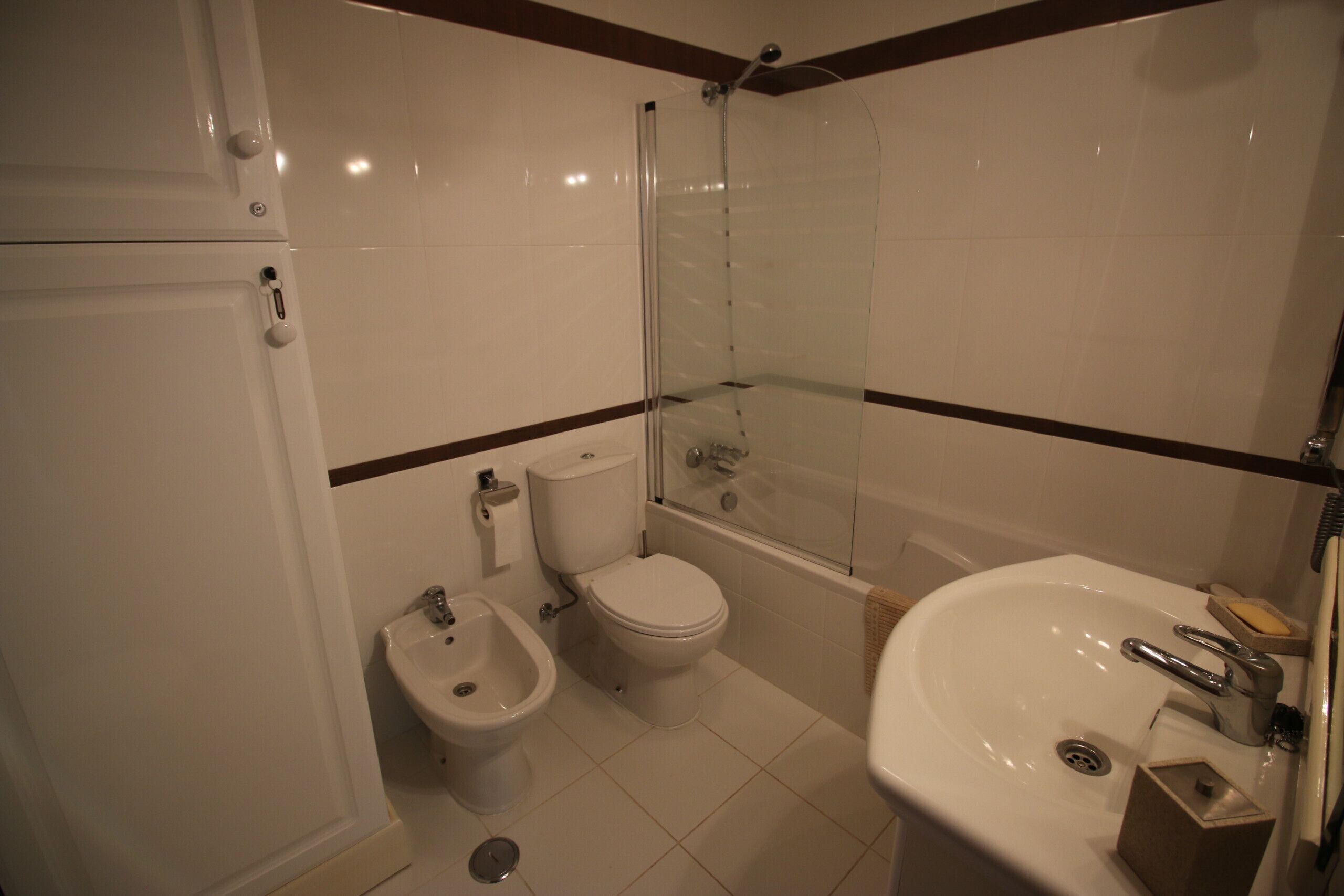 Un baño con inodoro, bidé, ducha y lavamanos.
