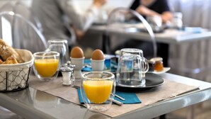 A breakfast setting with a table set for two, including a basket of croissants, glasses of orange juice, and a coffee pot. - Hôtel du Golfe (Balaruc-les-Bains)