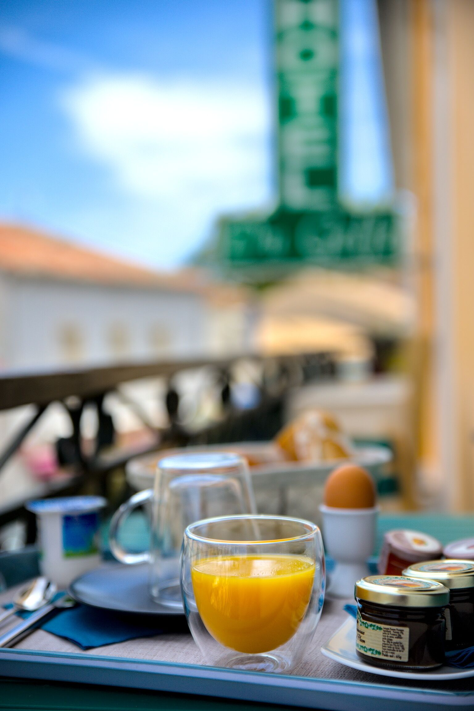 Ein Frühstückstisch mit Orangensaft, einer Tasse, einem Teller mit Speisen und Gewürzen.