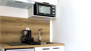 A compact kitchenette with a microwave, coffee maker, and a small refrigerator. - Hôtel du Golfe (Balaruc-les-Bains)