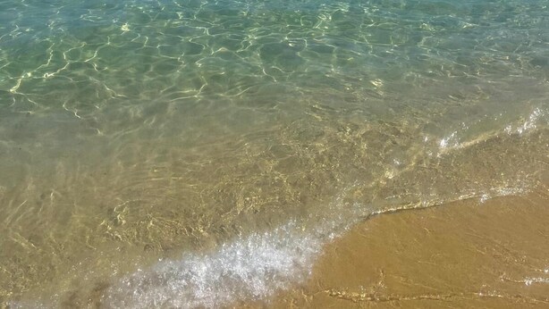 Une plage avec une eau claire et peu profonde et un rivage sablonneux.