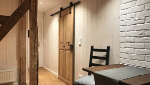 A wooden-framed staircase, a wooden door, a white brick wall, and a table with a checkered cushion. - Klein Bullerbü im Alpbachtal Tegernsee (Tegernsee)