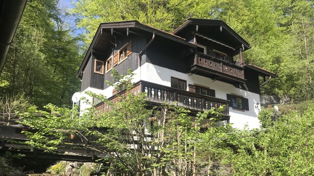 A multi-story chalet with balconies, surrounded by lush greenery and a small waterfall. - Klein Bullerbü im Alpbachtal Tegernsee (Tegernsee)