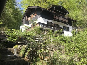 A multi-story chalet with balconies, surrounded by lush greenery and a small waterfall. - Klein Bullerbü im Alpbachtal Tegernsee (Tegernsee)