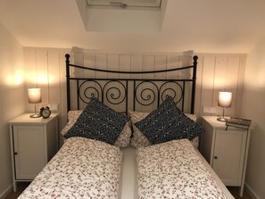 A double bed with floral bedding, two matching pillows, bedside lamps, and a small alarm clock on each nightstand. - Klein Bullerbü im Alpbachtal Tegernsee (Tegernsee)