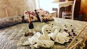 Ein Bett mit einer blumigen Tagesdecke, eine Champagnerflasche und eine zu einem Schwan geformte Handtuchgestaltung.