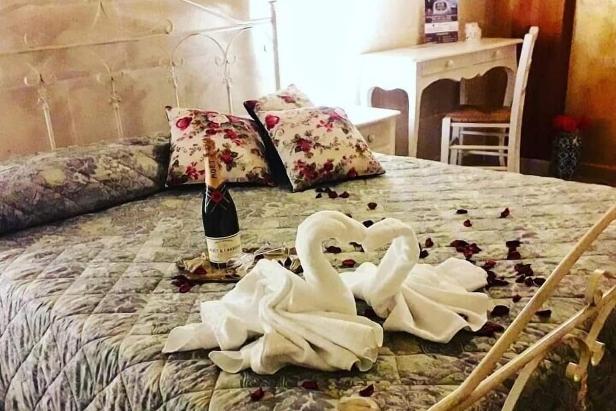 Uma cama com edredom floral, uma garrafa de champanhe e um arranjo de toalha em formato de cisne.