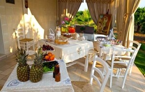 An outdoor dining area with a table set for a meal, surrounded by chairs. - B&B Giardino Isabella (Palagiano)