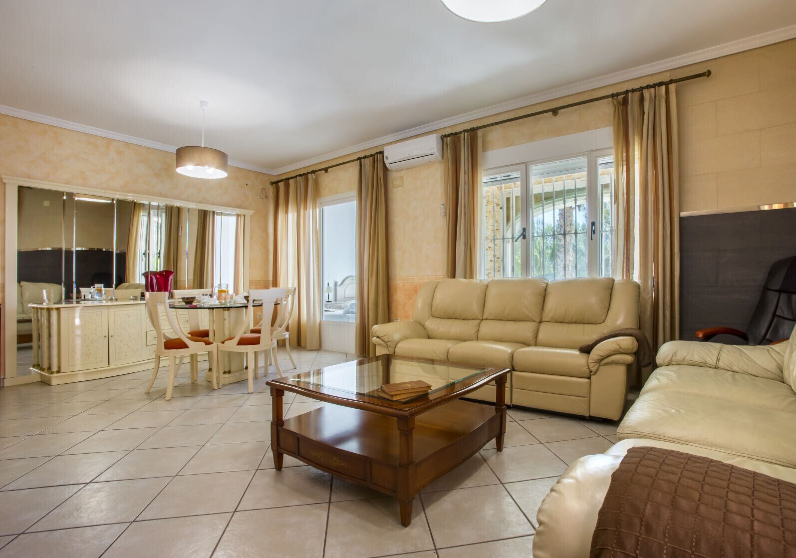 Un grand espace de vie comprenant un canapé, une table basse et un coin repas avec des chaises et une table.
