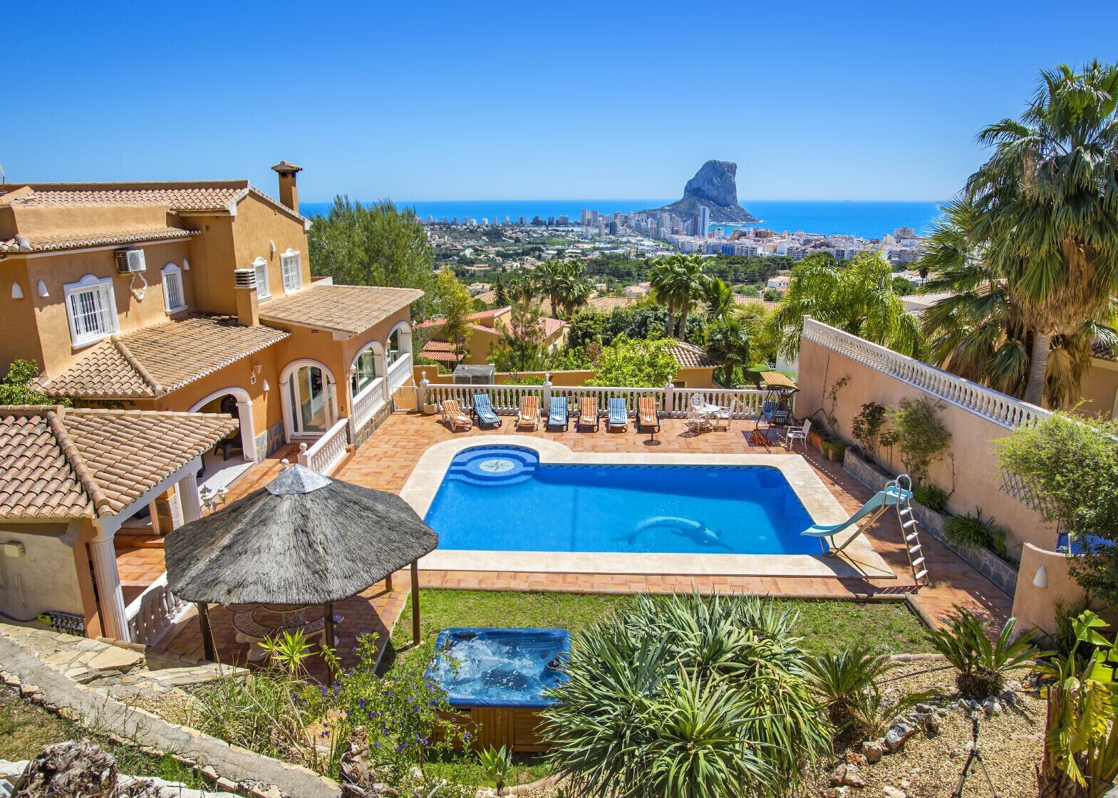 Zona de piscina con vista a la ciudad y una destacada formación rocosa.