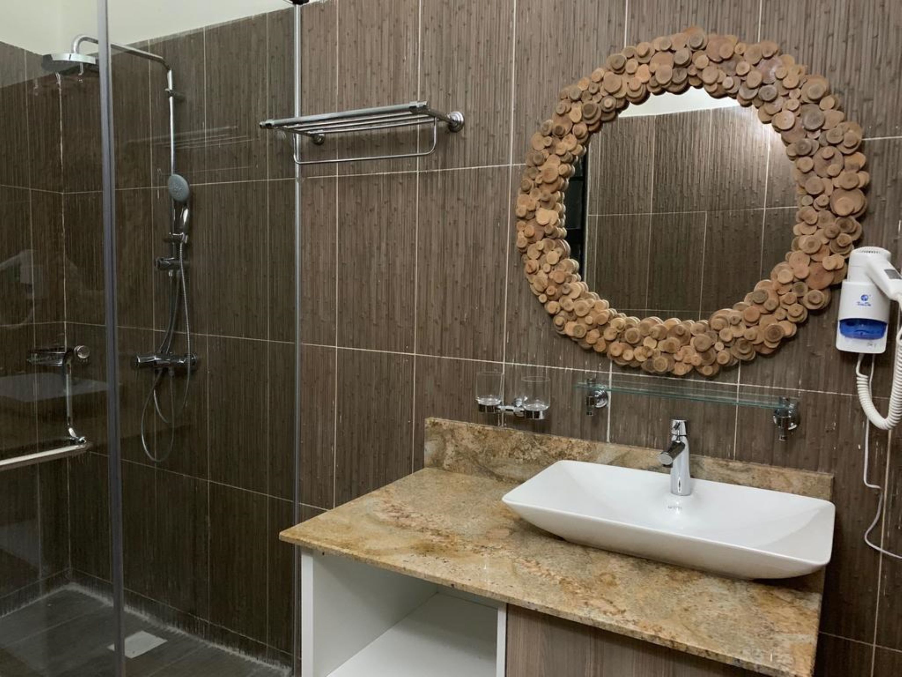 A modern bathroom with a glass-enclosed shower, a sink with a marble countertop, and a mirror surrounded by a wooden frame.