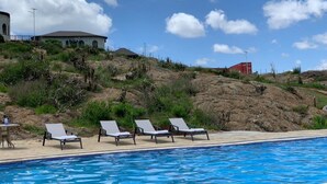 A swimming pool with lounge chairs, a building with a dome roof, and a rocky hillside. - Saab Royale Resort (Ilyagaleni)