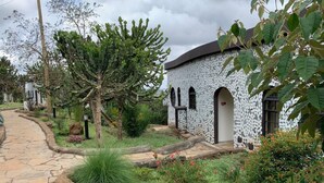 A building with a white exterior and dark roof, surrounded by lush greenery and a stone pathway. - Saab Royale Resort (Ilyagaleni)