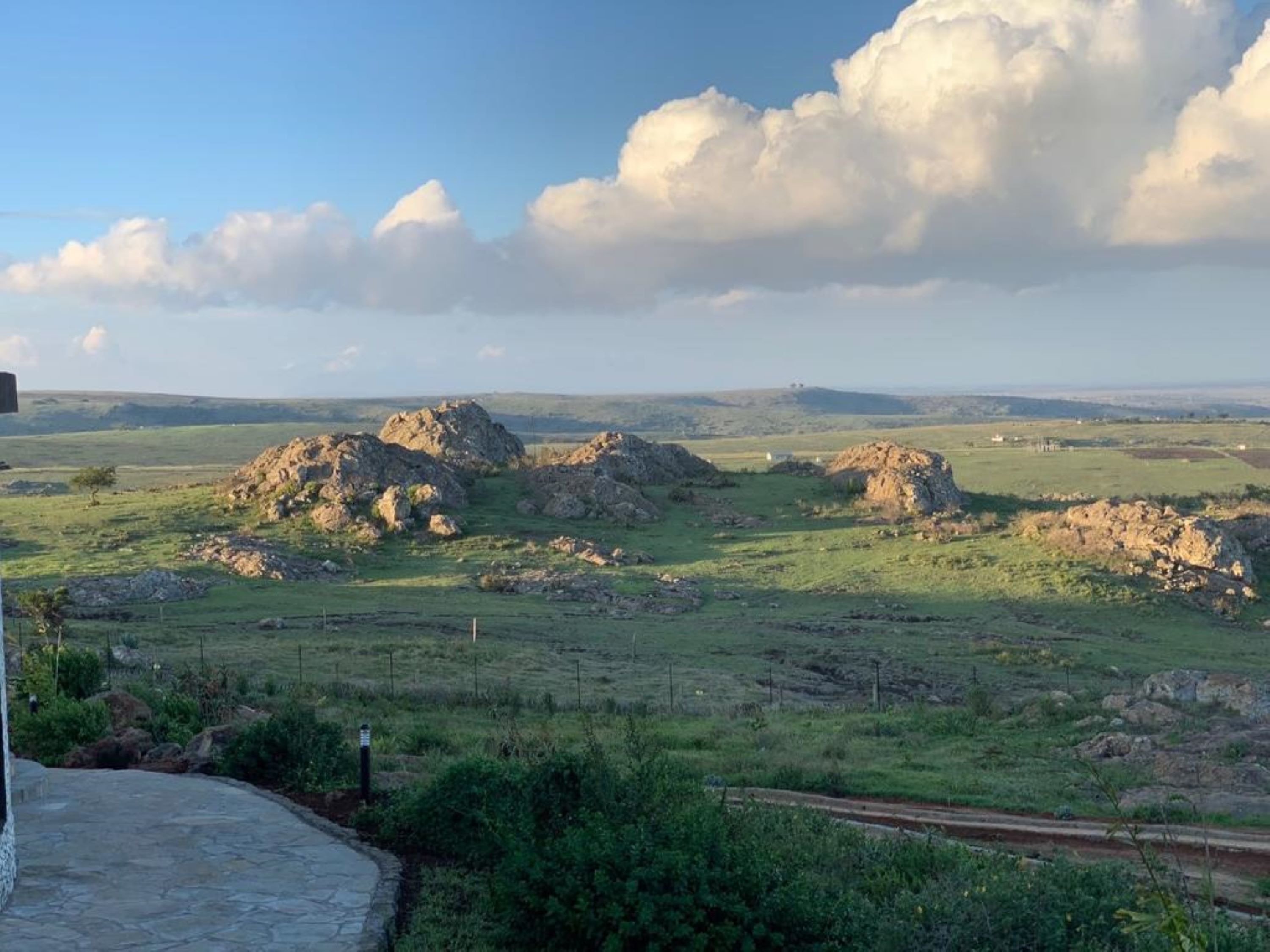 A rural landscape with rolling hills and scattered rocky outcrops.