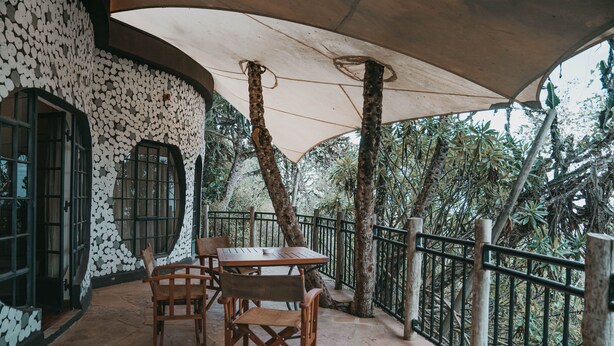 An outdoor patio with a table and chairs, surrounded by a stone wall and a metal railing. - Saab Royale Resort (Ilyagaleni)