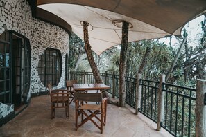 Un patio al aire libre con una mesa y sillas, rodeado de un muro de piedra y una barandilla de metal.