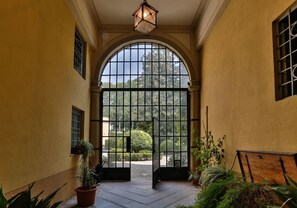 An arched entrance with a metal gate, potted plants, and a hanging light fixture. - CASA BEATRICE, Apartment with Private Garden inside the Walls of Lucca (Lucca)