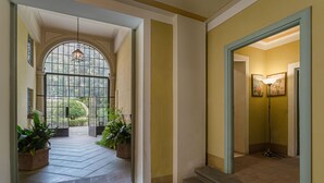 A hallway with a large arched window, potted plants, and a lamp. - CASA BEATRICE, Apartment with Private Garden inside the Walls of Lucca (Lucca)