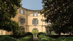 A building with a curved facade, multiple windows with shutters, and a central entrance. - CASA BEATRICE, Apartment with Private Garden inside the Walls of Lucca (Lucca)