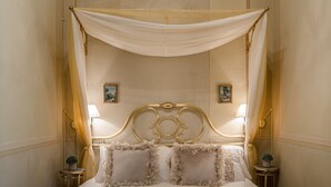 A bed with a canopy, two bedside tables with lamps, and two framed pictures on the wall. - CASA BEATRICE, Apartment with Private Garden inside the Walls of Lucca (Lucca)