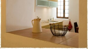 A kitchen with a window, a sink, and a pitcher on the counter. - Village Studio Apartment (Sablet)