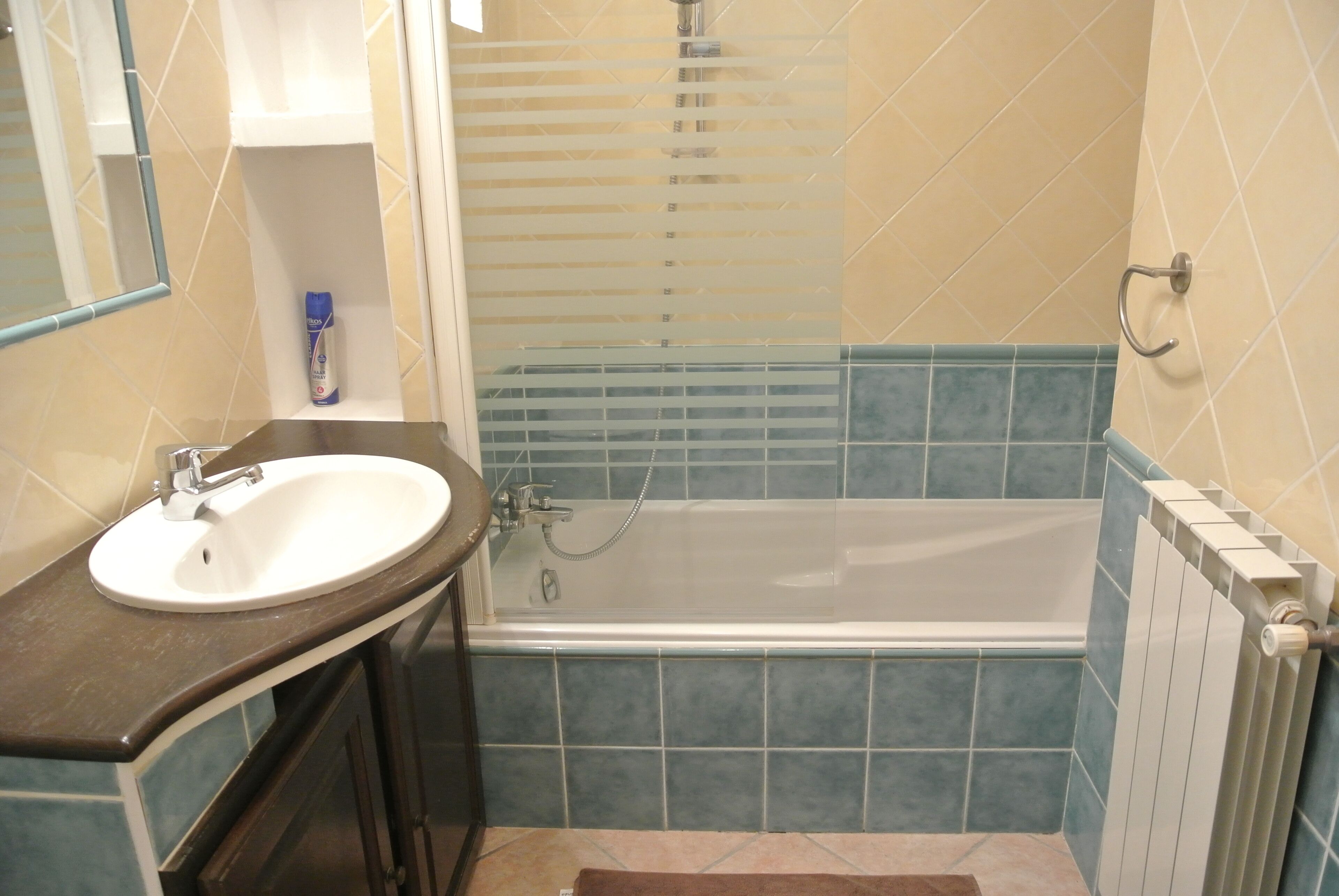 A bathroom with a sink, mirror, and bathtub.