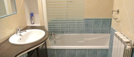 A bathroom with a sink, mirror, and bathtub.